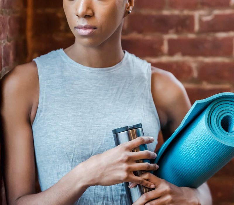 A clean and organized space with a rolled up yoga mat and a water bottle.